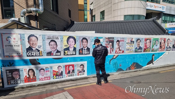  지난 5일 오후 대구 동인동행정복지센터 앞 담벼락에 붙어있는 대통령선거 후보 벽보를 한 시민이 유심히 바라보고 있다.