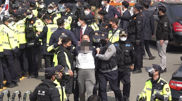 24일 낮 대구시 달성군 유가읍 박근혜 전 대통령 자택 앞에서 박씨를 향해 소주병을 던진 40대 이아무개씨가 경찰에 붙잡혀 끌려나오고 있다.