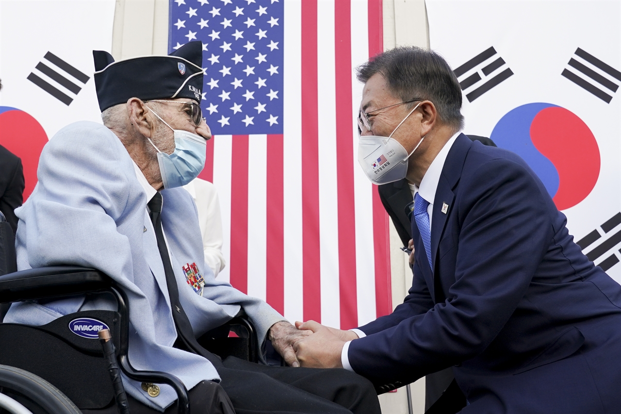  2021년 5월 22일 문재인 대통령이 미국 워싱턴 한국전 참전기념비 공원에서 열린 한국전 전사사 추모의 벽 착공식에서 참전용사인 윌리엄 웨버의 손을 잡으며 대화하고 있다.