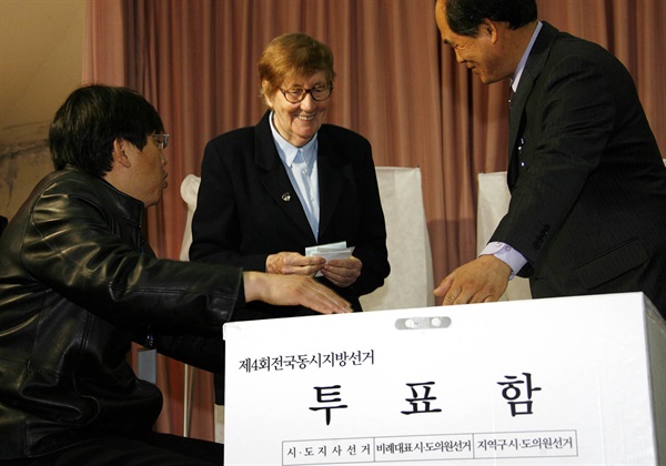 2006년 5.31 지방선거에서 처음으로 선거권이 주어지는 외국인 유권자가 2006년 4월 15일 서울 중구 한성화교소학교에서 열린 투표시연회에서 선관위 관계자의 안내를 받으며 직접 모의투표를 해보고 있다. 5.31 지방선거 선거권이 주어지는 외국인은 영주 체류자격 취득일 후 3년이 경과한 19세 이상의 자다. 