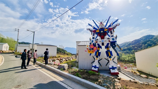 마을 초입에 세워진 만화 속 로봇 캐릭터의 대형 모형은 무기 대신에 꽃다발을 들고 있다.

