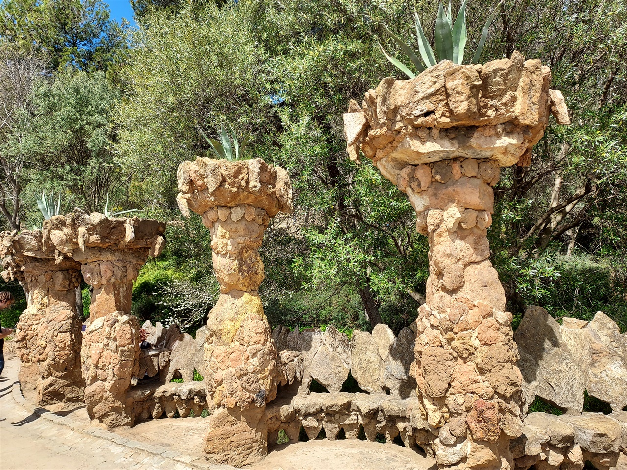 돌과 흙으로 만든 기둥 사이에 돌로 만든 벤치가 있는 산책길