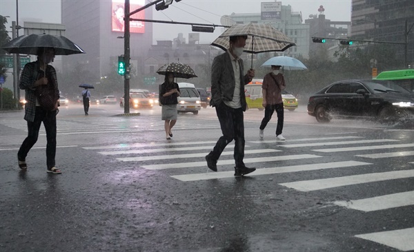 서울을 포함한 수도권에 호우특보가 발효되는 등 간밤에 많은 비가 내리면서 출근길 도심 곳곳 도로가 통제되고 있는 30일 오전 서울 광화문 세종대로 사거리에서 시민들이 출근하고 있다.