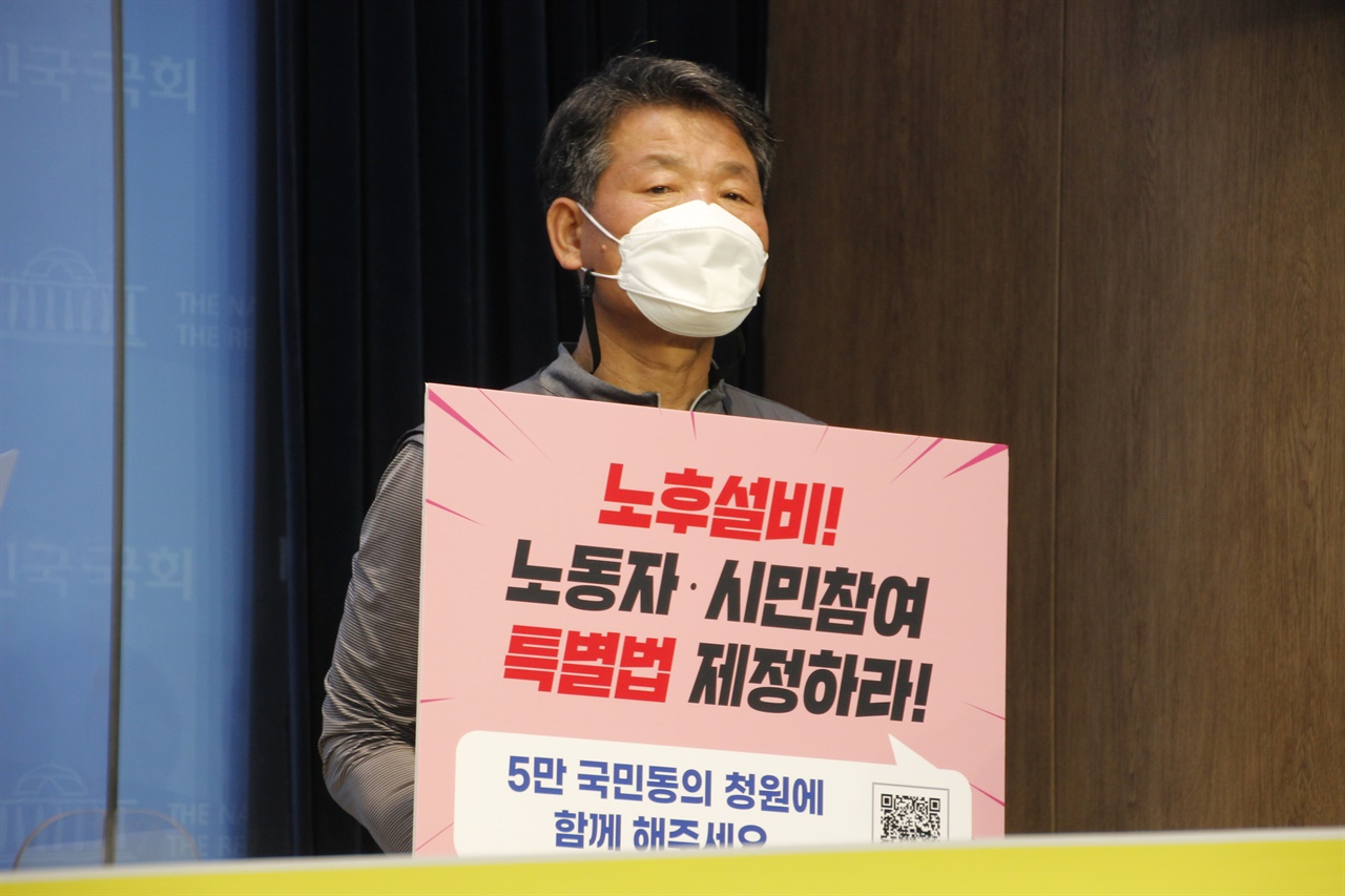 신환섭 화섬식품노조 위원장이 기자회견장에서 '노후설비특별법 제정 5만 국민동의 청원' 피켓을 들고 있다.