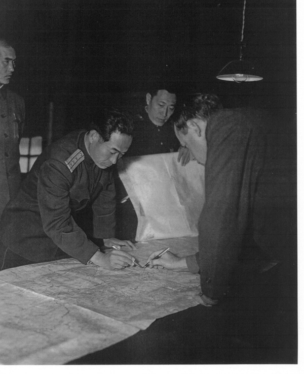 판문점 정전회담장에서 양측 실무자(북측 장평산 / 미측 머레이)들이 지도를 펴놓고 군사분계선을 긋고 있다.