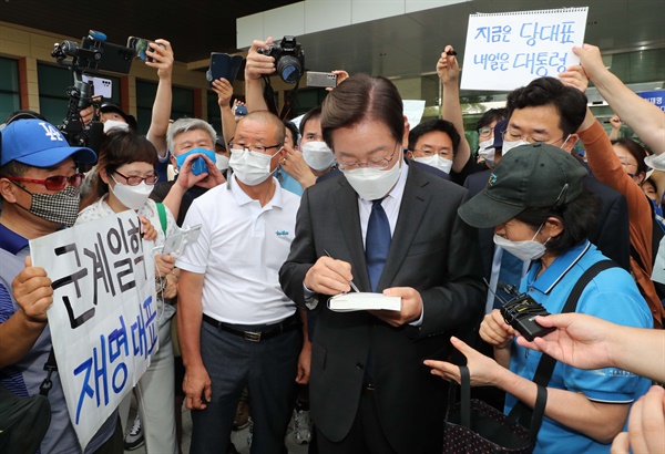  더불어민주당 이재명 의원이 17일 서울 여의도 국회 소통관에서 당대표 출마 기자회견을 마친 뒤 회견장을 나서며 지지자에게 사인해 주고 있다.