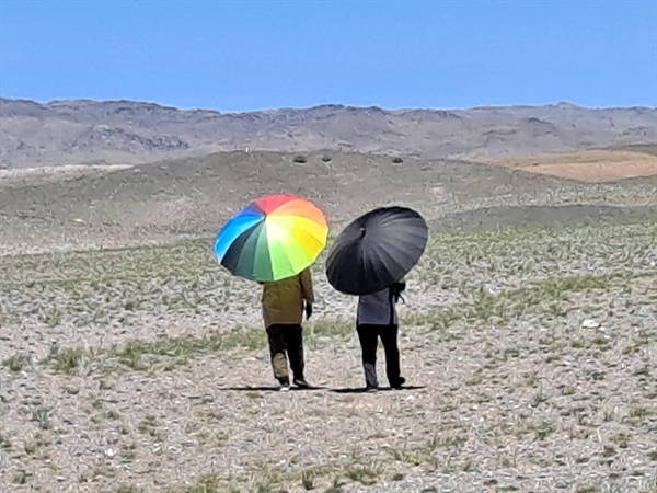 고조선유적답사단 일행 중 두 명의 여성이 화장실을 가기 위해 우산을 쓰고 멀리 가고 있다. 몸을 가려줄 것 하나 없는 사막에서 화장실에 가기 위해서는 우산이 대안이 된다.