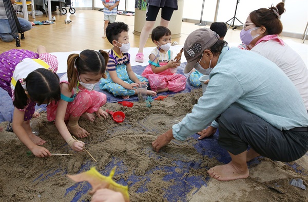 국내 모래조각 창시자인 김길만 작가가 아이들과 공룡 모형 모래조각을 만들고 있다. [엄아현 기자]