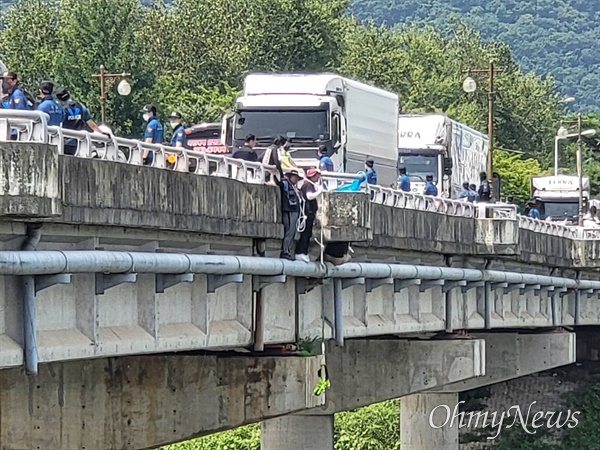 4일 강원 홍천군 하이트진로 강원공장 입구에서 민주노총 공공운수노조 화물연대 하이트진로지부 조합원 일부가 농성 중 다리 위 난간에 올라가 경찰 진압에 항의하고 있다.