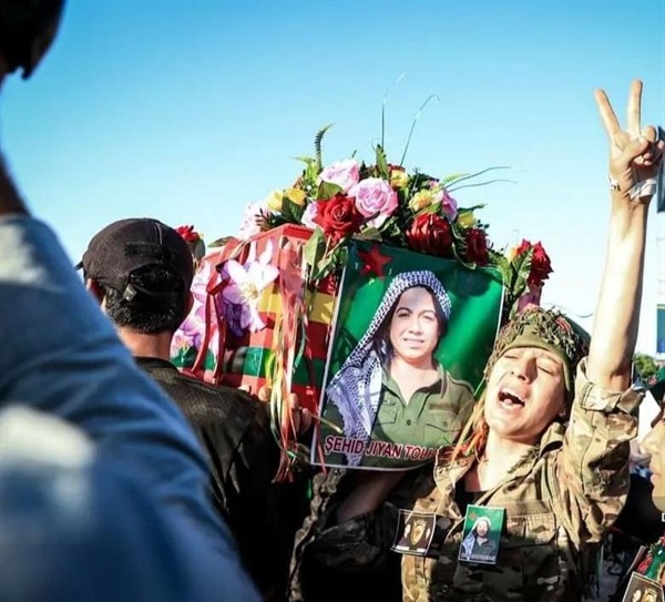 YPJ 여전사들이 전투 중 순교한 동료의 사진을 건 관을 메고 우열하고 있다. 순교자(Sehid)는 순교자 묘지에 안장 되고 가족은 존경 받는다. 쿠르드족은 한과 눈물이 많은 역사를 품고 있다.  