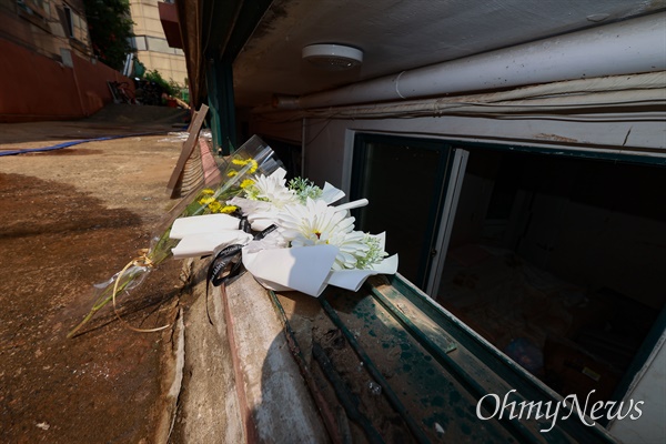 지난 8월 12일, 서울 관악구 신림동 한 빌라 뜯겨진 반지하 창틀 앞에, 앞서 침수된 반지하방에서 구출되지 못하고 숨진 3명을 추모하는 국화꽃이 놓여 있다.