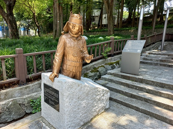  공원 입구 해태상 뒤에 시민군의 상징이 된 무명 열사 ‘김군’ 동상과 표지석이 서 있다. ‘평화의 소녀상’을 제작한 김서경·김운성 작가의 작품이다

