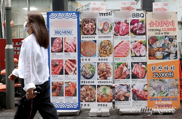 최근 물가의 고공행진으로 하루 한 푼도 쓰지 않는 ‘무지출 챌린지’가 청년세대에서 유행하고 있는 가운데, 25일 오후 서울 중구 명동에서 한 시민이 음식 광고판 앞을 지나가고 있다.
