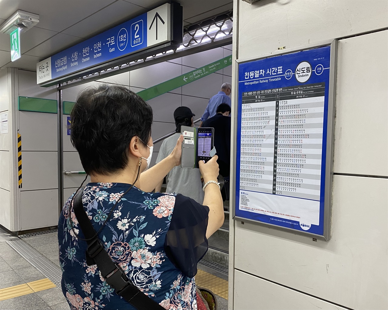 인쇄식 열차 시간표를 휴대폰으로 촬영하고 있는 시민