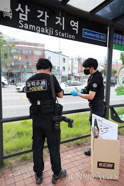  경찰들이 삼각지역 버스정류장에 붙은 윤석열 대통령 부부 풍자 포스터를 뜯어낸뒤 현장조사를 하고 있다.