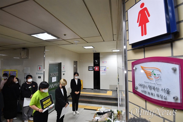 '역무원 스토킹 피살 사건'이 발생한 지난해 9월 16일, 사람들이 서울 지하철 2호선 신당역 여자화장실 입구에 마련된 추모공간을 찾아 추모하는 모습. 그럼에도 '여성이 행복한 서울'이라고 적힌 간판이 눈에 띈다.
