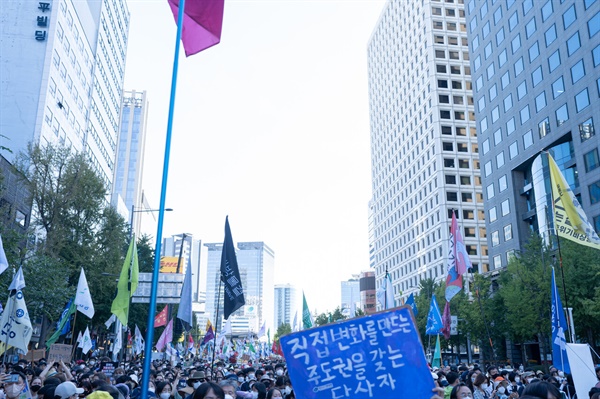 “직접 변화를 만드는 주도권을 갖는 당사자”라고 적힌 피켓 뒤로, 행진에 참여한 시민들의 모습 (사진 : 김연웅 기자)