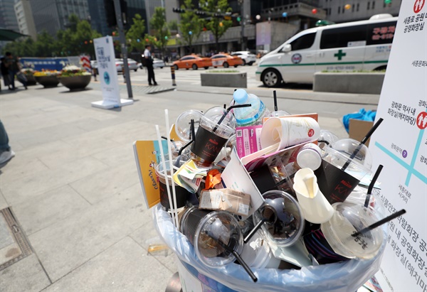 거리에 설치된 쓰레기통에 음료 컵이 무질서하게 버려져 있다.