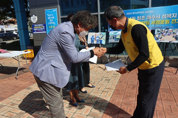 여수시 삼산면 초도 대동리 김진수 이장(왼쪽)이 임채욱 이사장에게 서명지를 전달하고 있다

