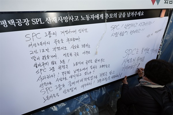 2022년 10월 20일 오후 서울 양재동 SPC 본사 앞에서 열린 평택 SPC 계열사 SPL의 제빵공장 사망 사고 희생자 서울 추모행사에서 한 시민이 추모의 글을 남기고 있다. 