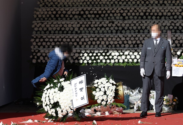 4일 오후 서울 중구 서울시청 앞 서울광장에 마련된 이태원 참사 희생자 합동 분향소에 이번 참사로 아들을 잃은 한 유족이 당일 부실대응에 항의하며 윤석열 대통령과 오세훈 서울시장의 근조화환을 쓰러뜨리고 있다.