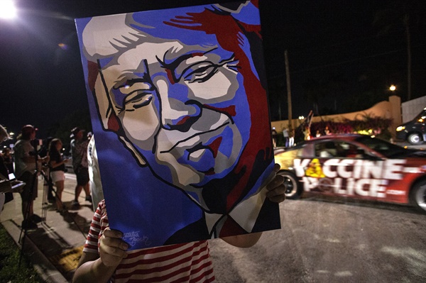 도널드 트럼프 전 미국 대통령의 지지자들이 11월 15일 미국 플로리다주 마러라고 리조트에서 트럼프 전 대통령의 얼굴이 그려진 깃발을 들고 있다.