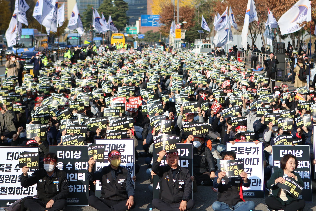 전국철도노동조합 서울지방본부 조합원들이 "더 이상 죽이지 마라! 안전인력 충원!"이라고 적힌 손팻말을 들고 구호를 외치려 하고 있다. 