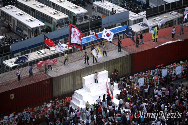 미국산쇠고기 수입 전면 재협상 촉구 및 국민무시 이명박 정권 심판 100만 촛불대행진에 참석했던 시민, 학생들이 11일 새벽 서울 세종로네거리에 설치된 경찰 컨테이너 바리케이트 위에 올라가서 태극기와 깃발을 흔들고 있다.