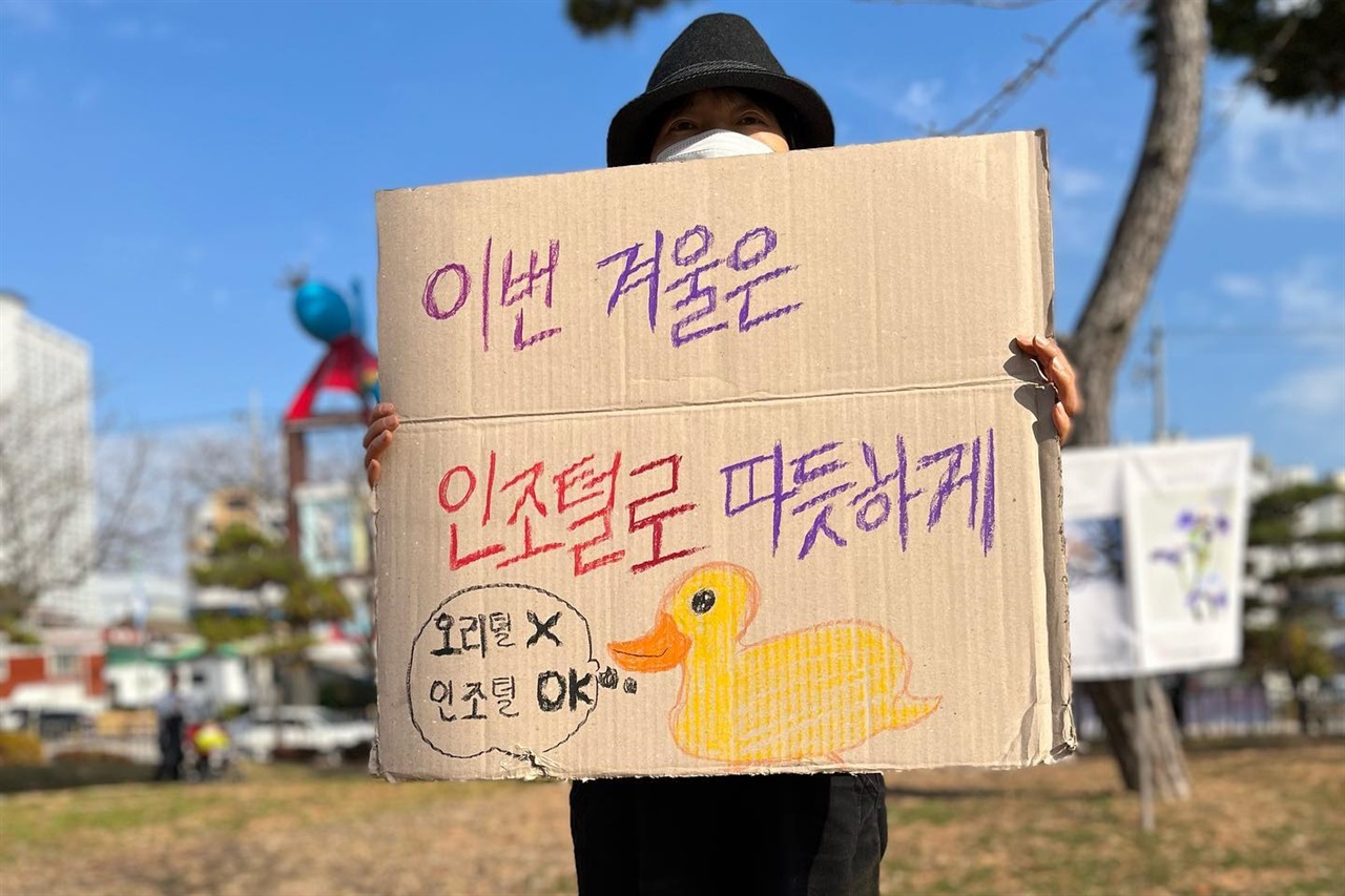 서산동물권행동 회원이 인조 털로 만든 옷을 구입할 것을 권유하는 손팻말을 들고 있다.