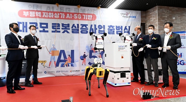 11월 25일 부평지하상가에서 열린 '부평역 지하상가 AI·5G 기반 대규모 로봇실증사업 출범식'에서 내빈과 로봇이 현판을 제막하고 있다.