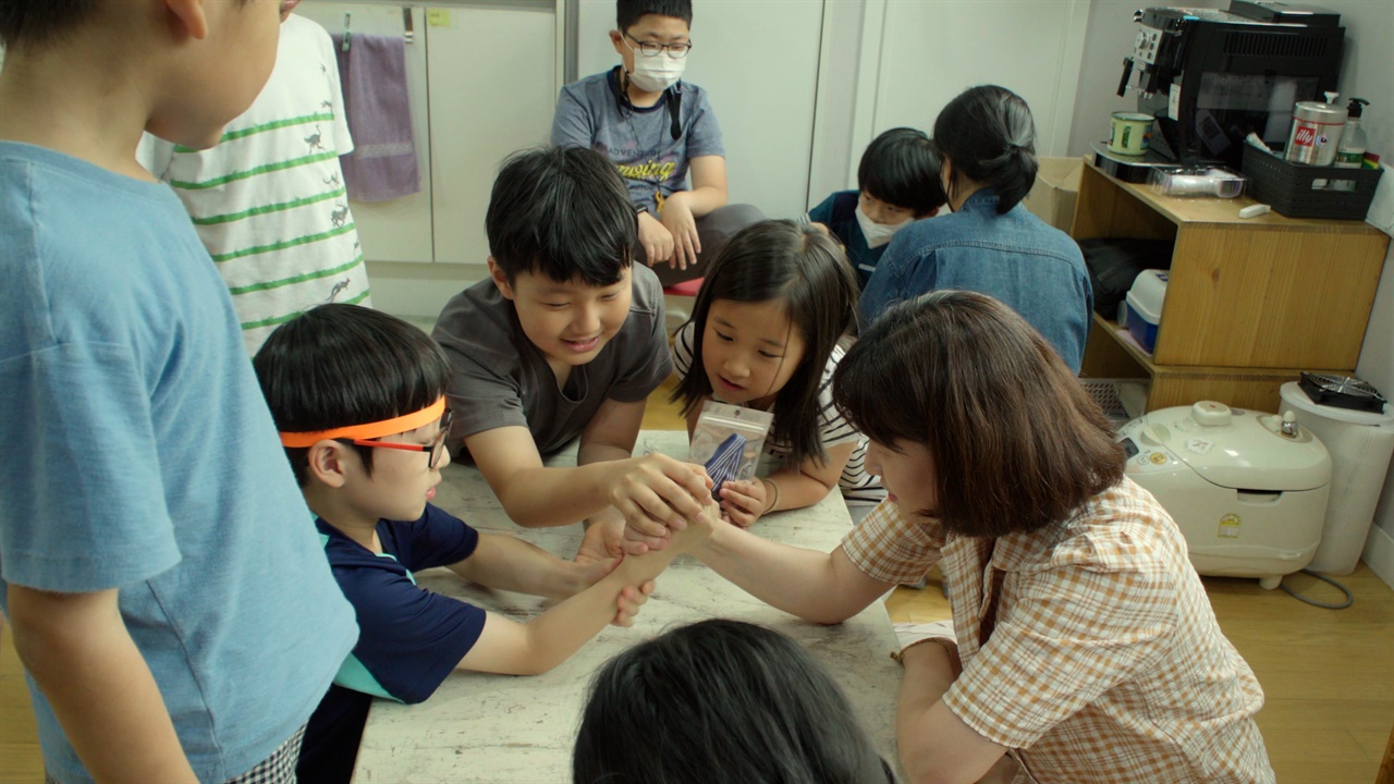  아이들과 팔씨름 중인 마을 방과후 선생님. 도전을 해오는 아이들도 선생님이라고 봐주지 않고 도전을 받는 선생님도 아이라고 봐주지 않는다.