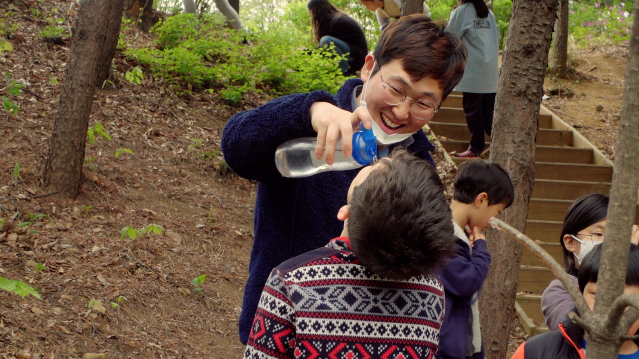 마을 방과후 아이들은 마을에 있는 작은 산 성미산에 자주 오른다. 깜박하고 물통을 가져오지 않는 아이에게 물을 나눠주고 있는 마을 방과후 선생님