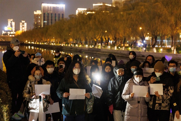 11월 27일 중국 베이징에서 열린 우루무치 화재 참사 추도식 도중 시민들이 코로나19 봉쇄 조치에 반대하며 백지를 든 '백지시위'를 하고 있다. 