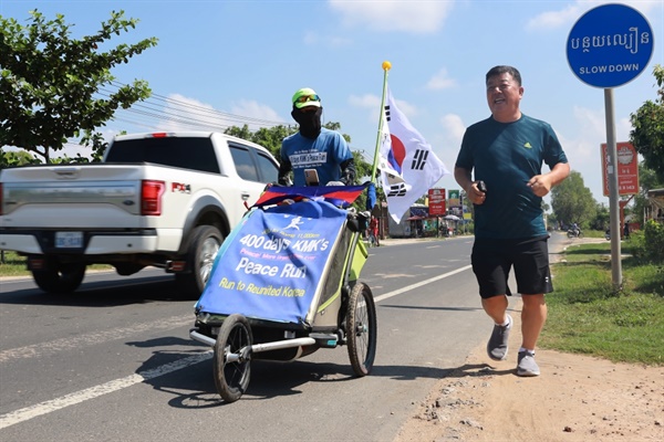 한 달여 거친 국내 달리기에 이어 해외 첫 출발지인 베트남을 거쳐  두번째 나라인 캄보디아 바벳 국경에 도착한 강명구 평화 마라토너가  마중 나온 정명규 캄보디아한인회장과 함께 수도 프놈펜을 향해 달리고 있다.