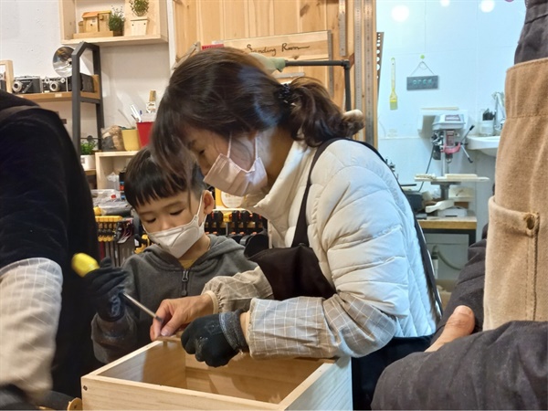  할머니와 손자가 함께 수납 상자를 만들고 있다.