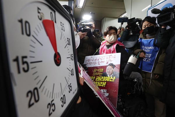 전국장애인차별철폐연대(전장연) 회원들이 2일 오전 서울 지하철 4호선 삼각지역 승강장에서 5분이 표시된 시계를 들고 지하철 탑승을 시도하고 있다.