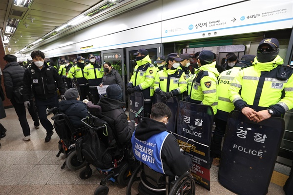 전국장애인차별철폐연대(전장연) 회원들이 1월 2일 오전 서울 지하철 4호선 삼각지역 승강장에서 지하철 탑승하려는 가운데 경찰이 배치돼 있다. 