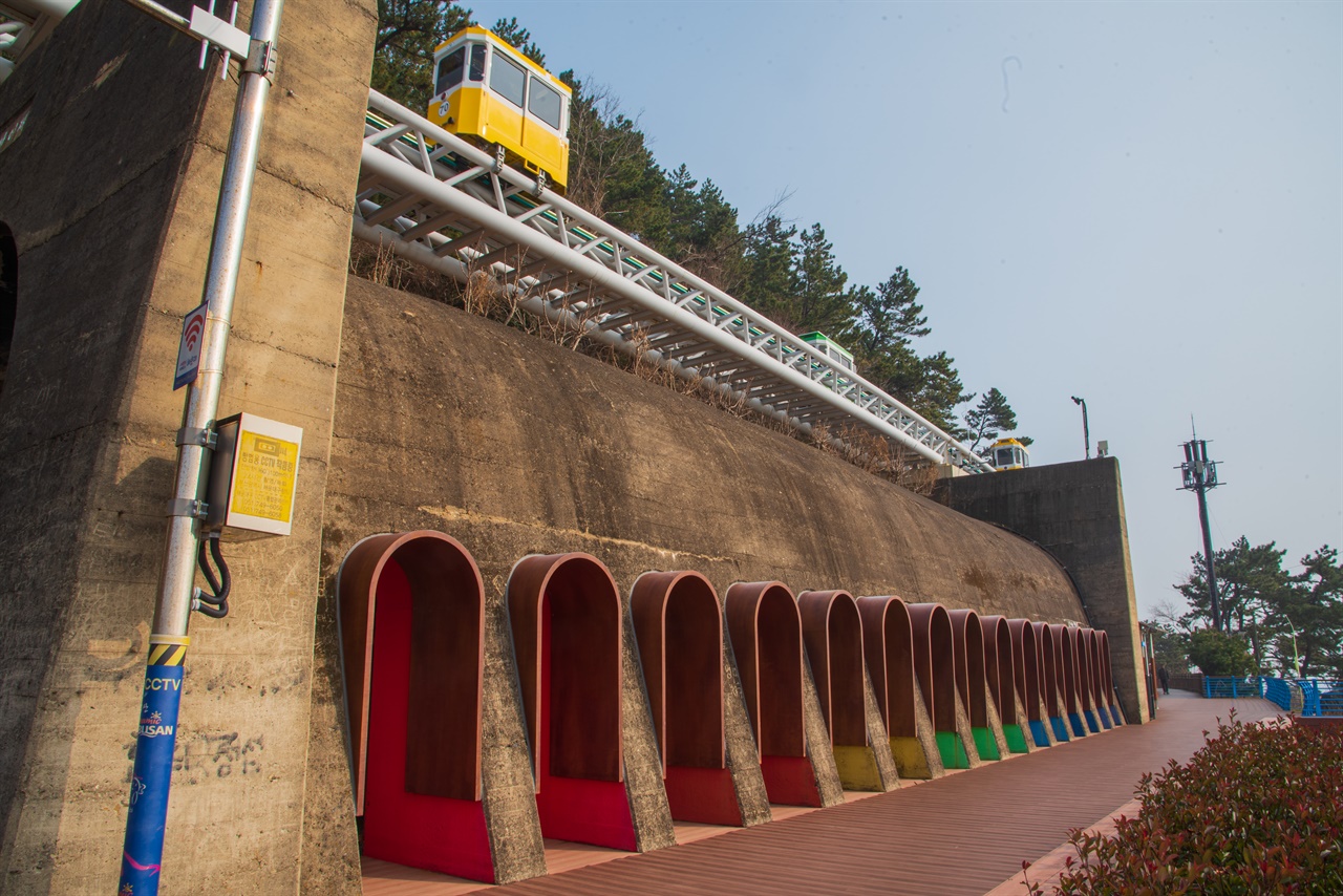 무지개 색 터널 조형물로 장식한 달맞이재터널. 그 위에 노란색 케이블카처럼 생긴 것이 스카이캡슐이다.