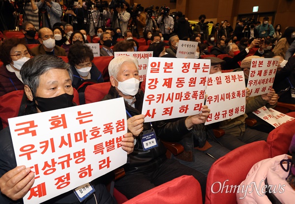 12일 오전 서울 여의도 의원회관 대회의실에서 열린 강제징용 해법 논의를 위한 공개토론회에서 피해 유가족과 참석자들이 일본 정부의 사과를 촉구하는 피켓을 들어보이고 있다.