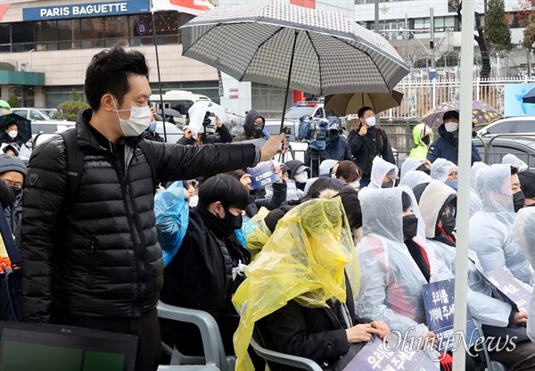 14일 오후 서울 용산구 대통령실 인근에서 열린 10.29 이태원 참사 3차 시민추모제 도중 비가 내리자, 한 시민이 우산을 꺼내 유가족이 비에 젖지 않도록 들고 있다.