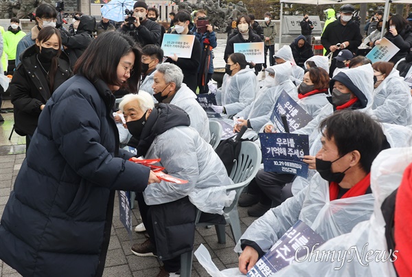 용혜인 기본소득당 의원이 14일 오후 서울 용산구 대통령실 인근에서 열린 10.29 이태원 참사 3차 시민추모제에 참석해 비가 오며 추운 날씨에 참석한 유가족에게 핫팩을 나눠드리고 있다.
