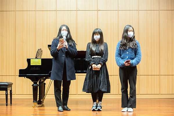 콘서트 중간 무대에 올라 <초록 가마우지 노래>  출판 후기를 말하고 있는 세 명의 고등학생 작가들