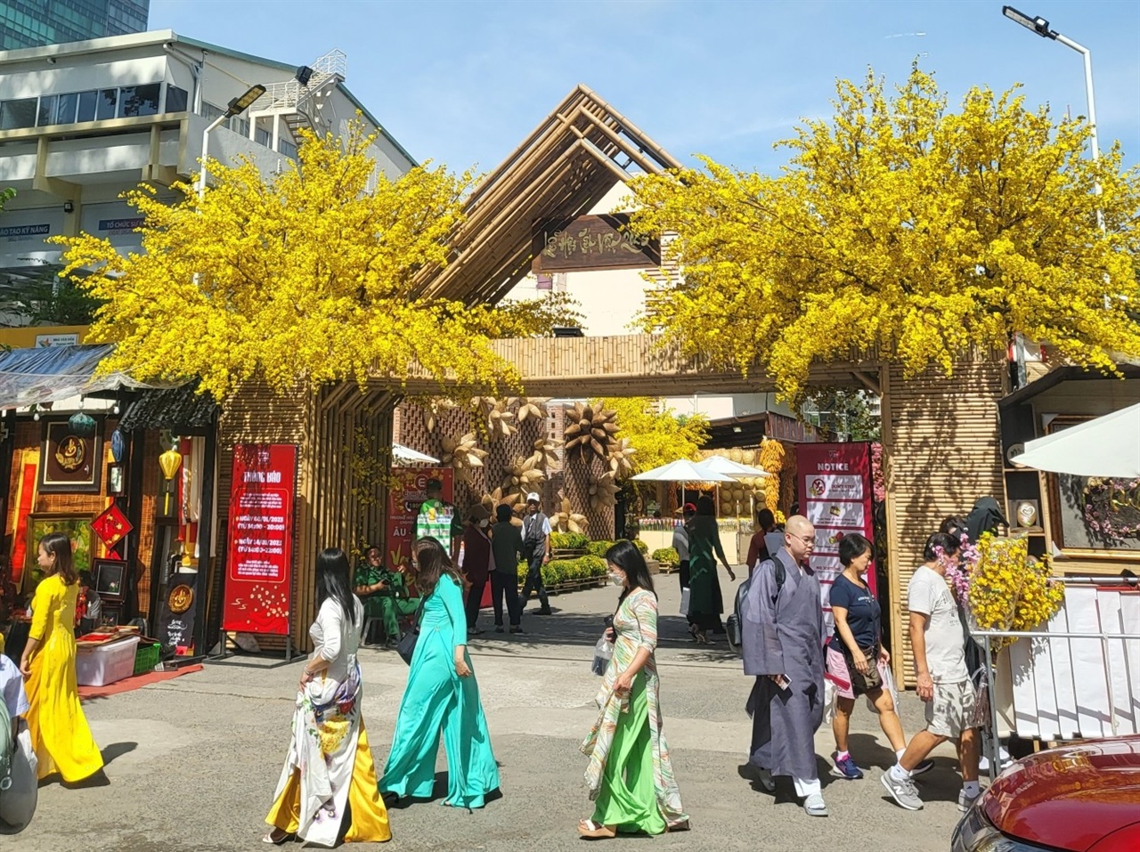 노란 꽃나무 아래서 사진을 찍기위해 아오자이를 차려입은 호치민 시민들