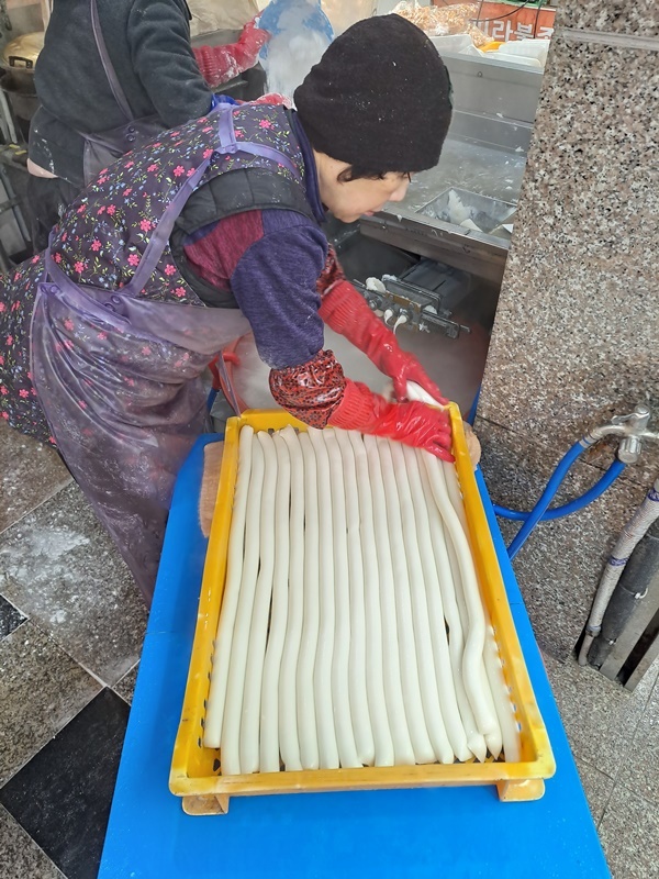  찜기에서 쪄낸 떡쌀을 이용해 가래떡을 뽑고 있다.  