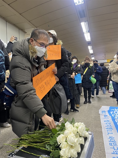 시민노래행동에 참가한 시민이 피켓을 들고 오이도역 참사 희생자를 추모하는 장미꽃을 헌화하고 있다. 