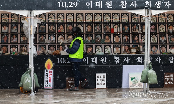지난 1월 26일 오전 서울 용산구 녹사평역 부근 이태원참사 희생자 합동분향소에 눈이 내리는 가운데 자원봉사자가 분향소를 정리하고 있다.