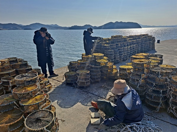 정종현 작가가 달천 바닷가에서 낙지잡이 통발을 보수하고 있는 어부 부부를 촬영하고 있다. 