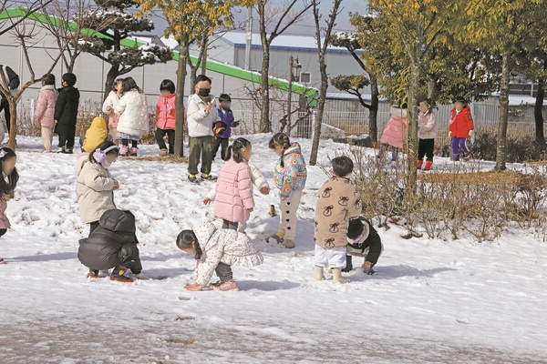 눈이 온 다음날 유치원 운동장에서 놀고 있는 아이들.