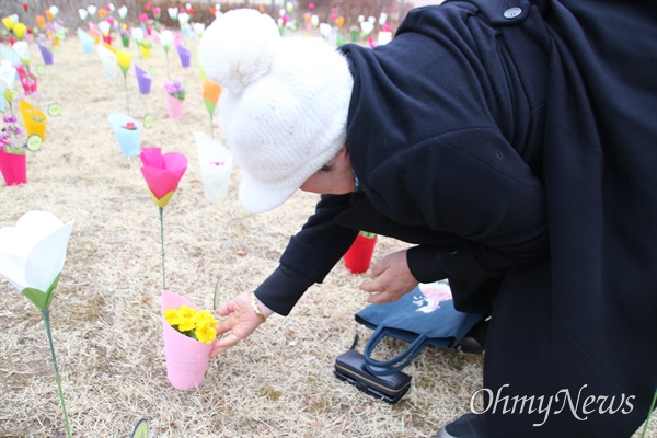 대구지하철참사 20주기 추모식이 열린 18일 오전 대구시민안전테마파크 추모탑 옆에 192명의 희생자를 추모하는 꽃이 꽃혀 있다. 한 유족이 자신의 자녀 이름이 새겨진 꽃을 어루만지고 있다.