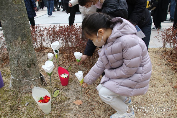대구지하철참사 20주기 추모식이 열린 18일, 한 어린이가 추모탑 옆 희생자들의 유골이 묻혀 있는 나무 밑에 꽃을 꼽고 있다.
